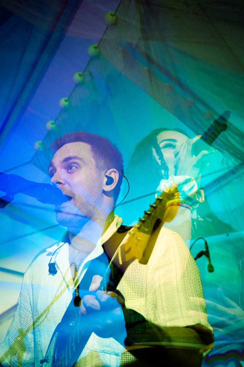 Sänger von Flashback Frenzy mit Gitarre, Bühnenlicht in Blau und Grün